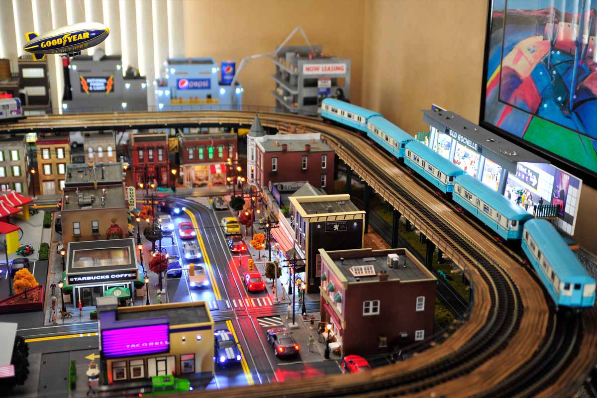 deadhead railways - model trains - blue train elevated over modern city